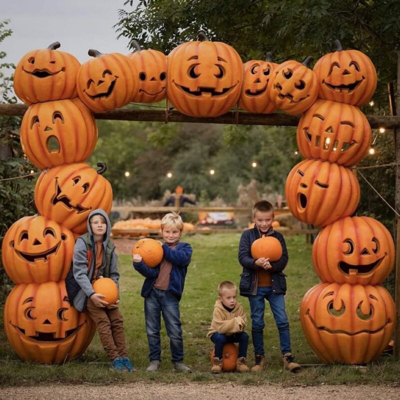 Pumpkin arcw with 4 boys standing underneath with a pumpkin in theur arms